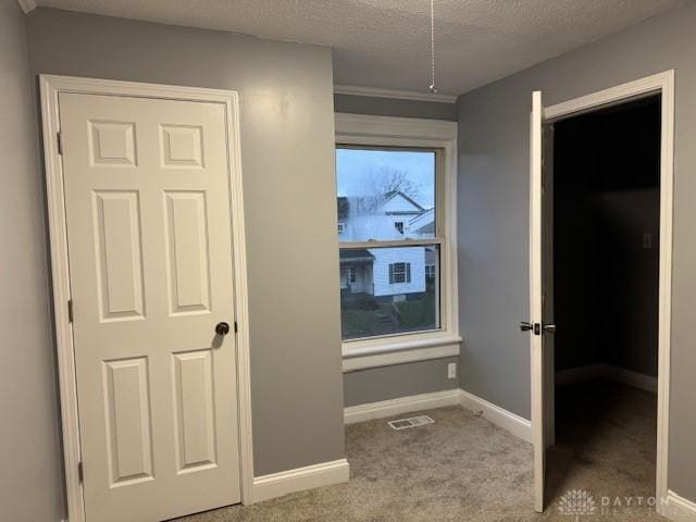 hall with a textured ceiling and light carpet