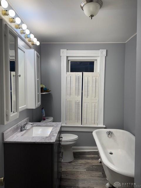 bathroom featuring ornamental molding, vanity, a bath, wood-type flooring, and toilet