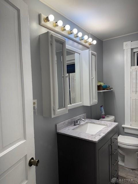 bathroom with crown molding, vanity, wood-type flooring, and toilet