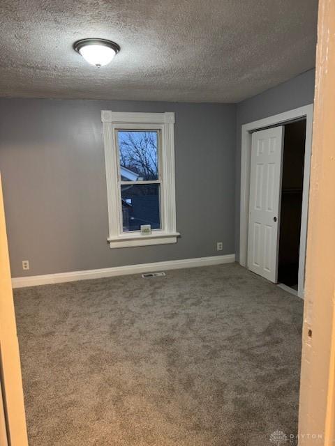 empty room with carpet floors and a textured ceiling