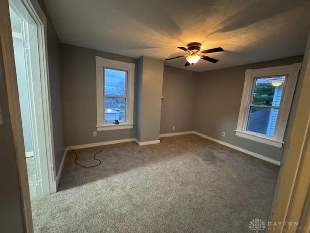 carpeted empty room with ceiling fan and a healthy amount of sunlight