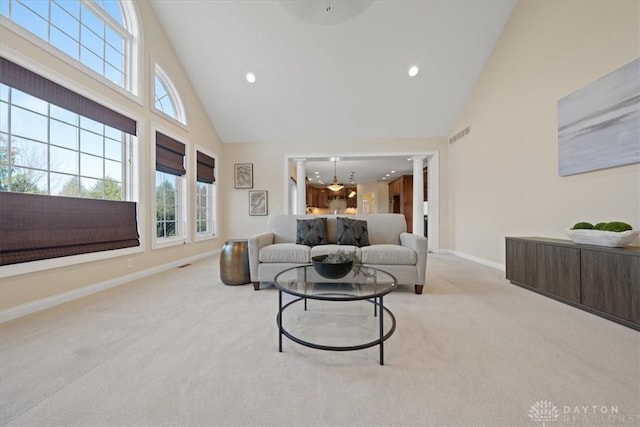 carpeted living room featuring ornate columns and high vaulted ceiling