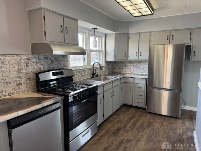 kitchen with backsplash, sink, hanging light fixtures, dark hardwood / wood-style floors, and stainless steel appliances