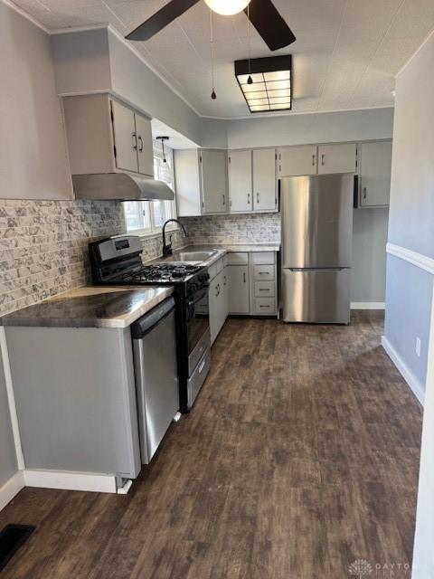 kitchen featuring dark hardwood / wood-style flooring, gray cabinetry, stainless steel appliances, ceiling fan, and sink