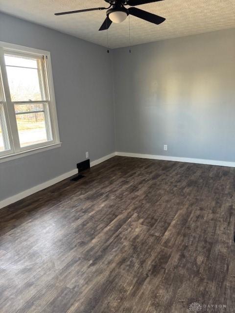 spare room with a textured ceiling, ceiling fan, and dark wood-type flooring