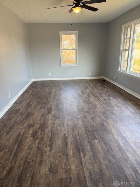 empty room featuring a textured ceiling, ceiling fan, and dark wood-type flooring