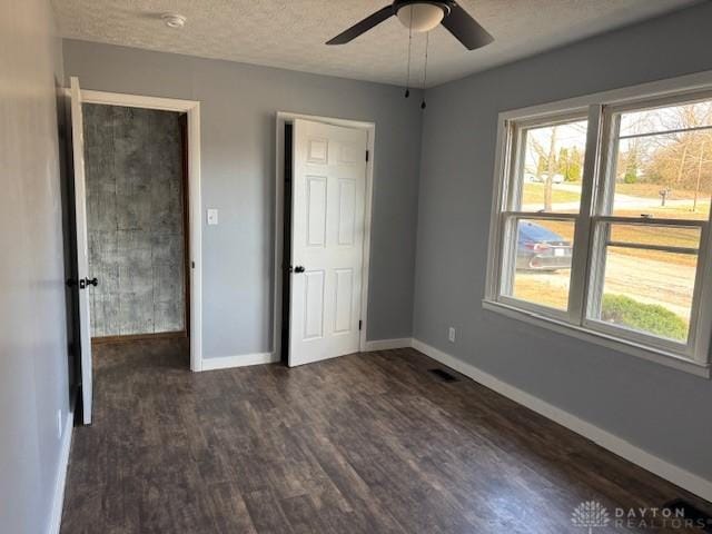 unfurnished bedroom with a textured ceiling, ceiling fan, and dark wood-type flooring