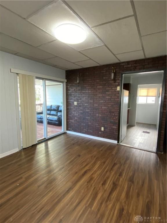 empty room with hardwood / wood-style flooring, a paneled ceiling, and a healthy amount of sunlight