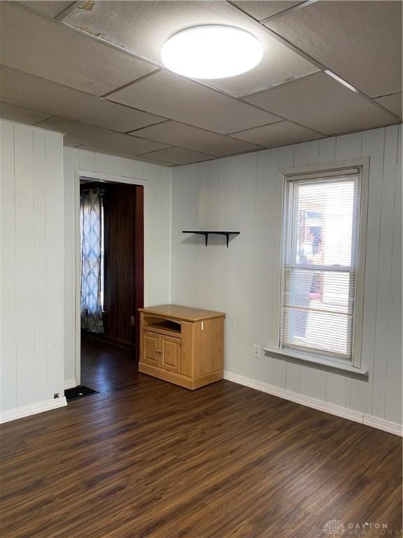 spare room featuring dark hardwood / wood-style floors, a drop ceiling, and wooden walls