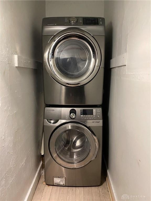 washroom with stacked washer and clothes dryer and light wood-type flooring