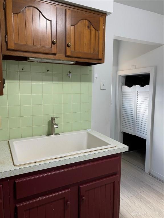 kitchen featuring decorative backsplash, sink, and light hardwood / wood-style flooring