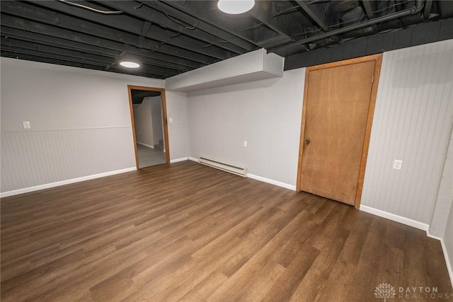 basement featuring a baseboard heating unit and hardwood / wood-style floors