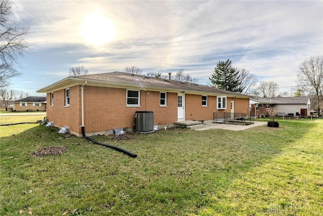 rear view of house with a patio, central AC unit, and a lawn