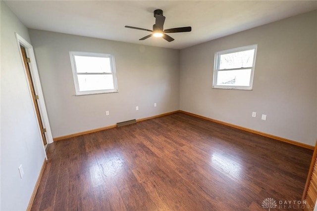 spare room featuring dark wood-type flooring, a wealth of natural light, and ceiling fan