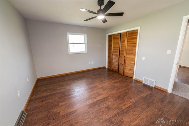 unfurnished bedroom featuring dark wood-type flooring, ceiling fan, and a closet