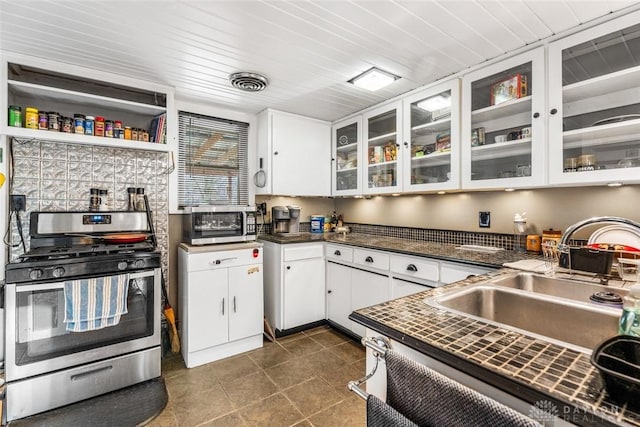 kitchen with gas stove, white cabinetry, and sink