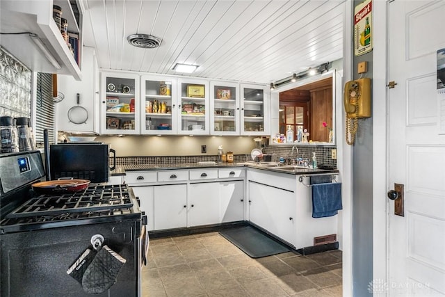 kitchen with decorative backsplash, black range with gas stovetop, white cabinetry, and sink