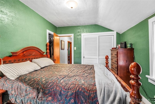 bedroom with lofted ceiling, a textured ceiling, and a closet