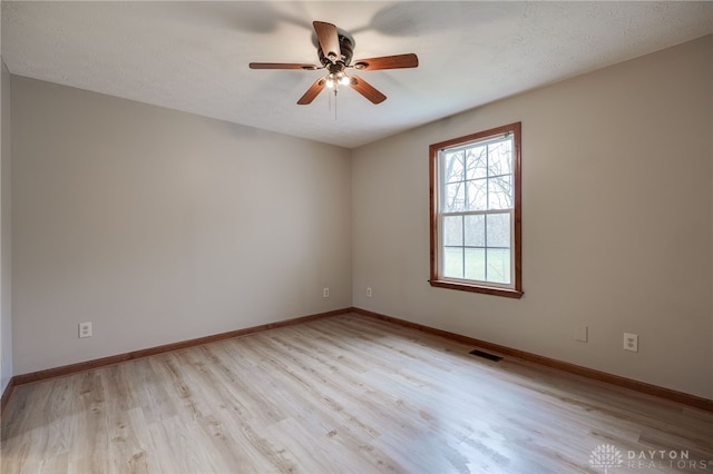 empty room featuring ceiling fan, light hardwood / wood-style floors, and a textured ceiling