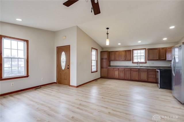 kitchen featuring stainless steel fridge, a healthy amount of sunlight, light hardwood / wood-style floors, and hanging light fixtures