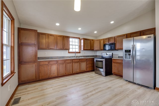 kitchen featuring sink, light hardwood / wood-style floors, vaulted ceiling, and appliances with stainless steel finishes