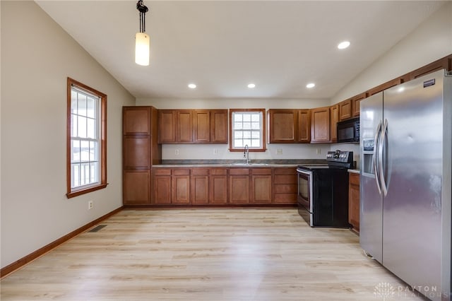 kitchen with light wood-type flooring, sink, black appliances, pendant lighting, and lofted ceiling