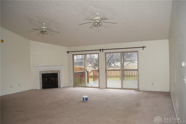 unfurnished living room with light carpet, a textured ceiling, a healthy amount of sunlight, and a tiled fireplace