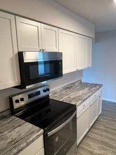 kitchen with white cabinets, light hardwood / wood-style flooring, stainless steel range with electric cooktop, and light stone counters