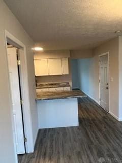 kitchen with kitchen peninsula, white cabinetry, and dark wood-type flooring