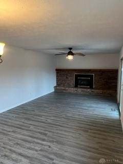 unfurnished living room with a wood stove, ceiling fan, and dark wood-type flooring