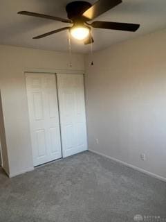 unfurnished bedroom featuring dark colored carpet, ceiling fan, and a closet