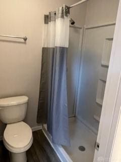 bathroom featuring curtained shower, hardwood / wood-style flooring, and toilet