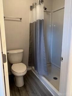 bathroom with hardwood / wood-style floors, curtained shower, and toilet