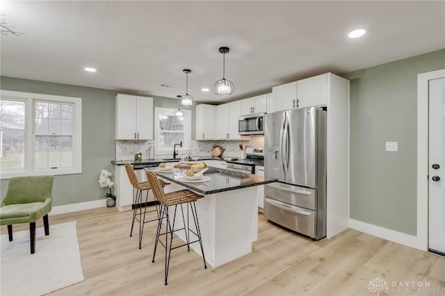 kitchen with white cabinetry, a center island, pendant lighting, stainless steel appliances, and decorative backsplash