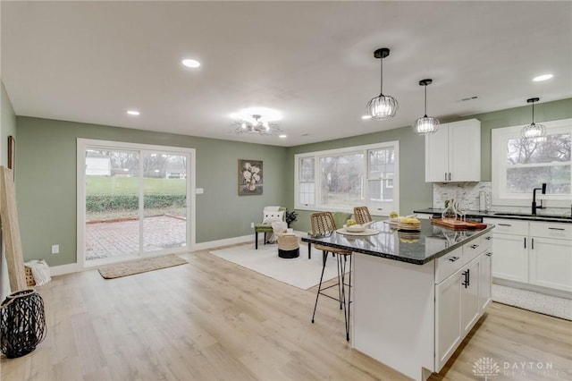 kitchen with backsplash, dark stone counters, light hardwood / wood-style floors, and white cabinets