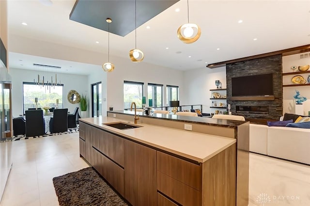 kitchen with pendant lighting, a fireplace, a spacious island, and sink