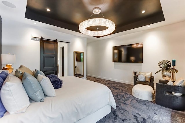 bedroom with a tray ceiling, a barn door, and dark carpet