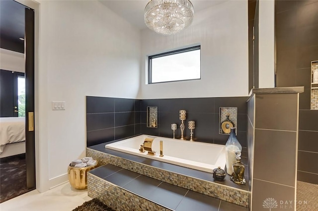 bathroom with tile patterned floors, a relaxing tiled tub, and a notable chandelier