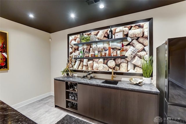 bar with black refrigerator, light wood-type flooring, and sink