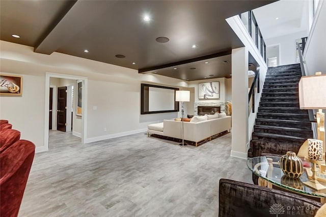 living room with hardwood / wood-style flooring, a stone fireplace, and beamed ceiling