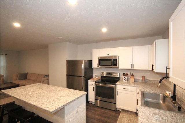 kitchen with white cabinetry, sink, dark hardwood / wood-style flooring, a kitchen island, and appliances with stainless steel finishes