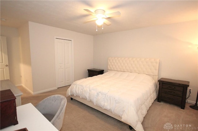 bedroom with ceiling fan, light colored carpet, and a closet