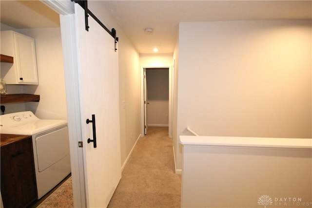 laundry room featuring cabinets, light carpet, a barn door, and washer / clothes dryer