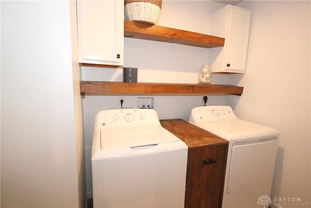 clothes washing area featuring washer and dryer and cabinets