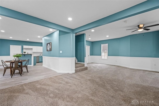 unfurnished living room with light carpet, beamed ceiling, and ceiling fan