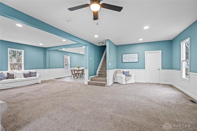 unfurnished living room with carpet flooring, beam ceiling, ceiling fan, and a healthy amount of sunlight