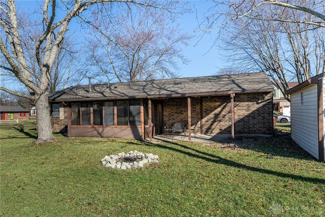 exterior space featuring a lawn, a sunroom, and an outdoor fire pit