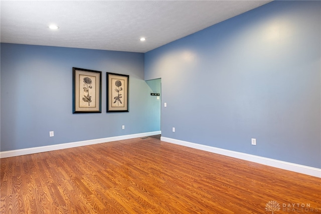 spare room with wood-type flooring, a textured ceiling, and lofted ceiling