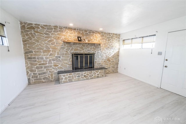 unfurnished living room featuring light hardwood / wood-style flooring and a stone fireplace