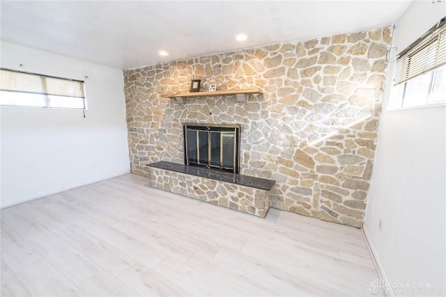 unfurnished living room with a stone fireplace and light wood-type flooring